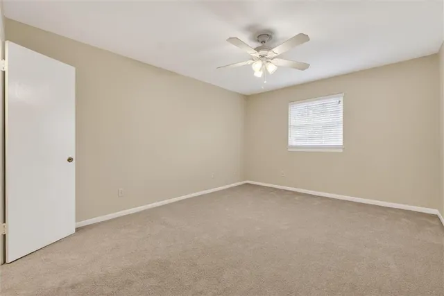 an empty room with a window and a fan