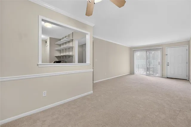 an empty room with chandelier fan and windows