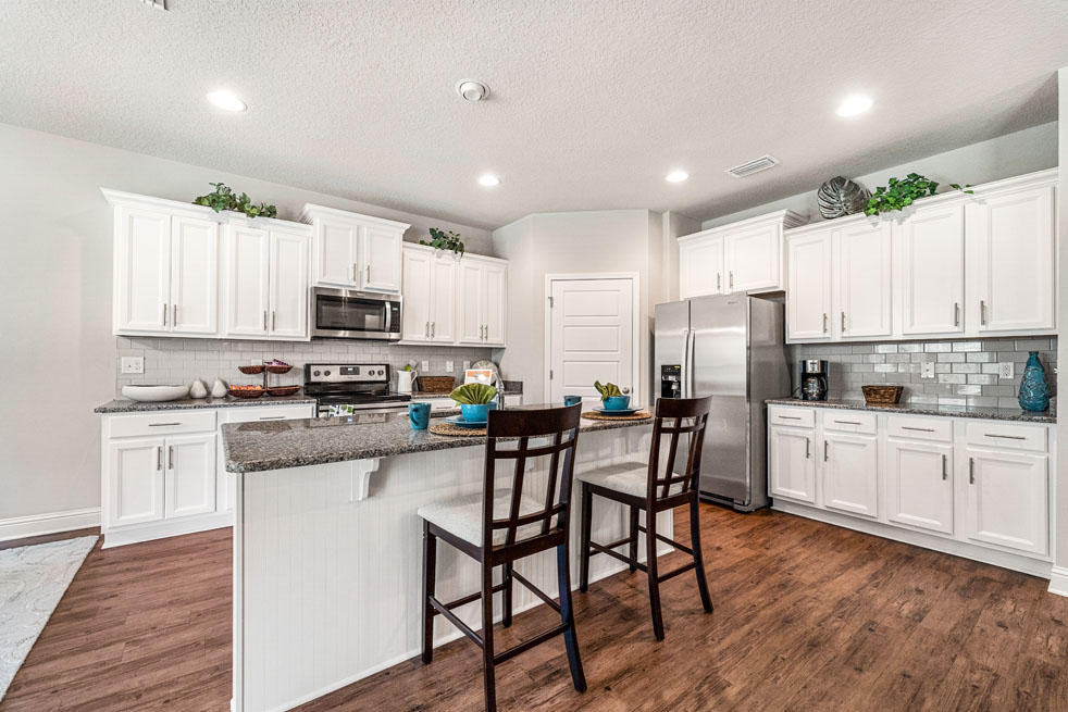 152 Conner Circle Santa Rosa Beach, FL 32459 - Photo 7 of 20 a kitchen with stainless steel appliances granite countertop white cabinets a sink a stove a dining table and chairs