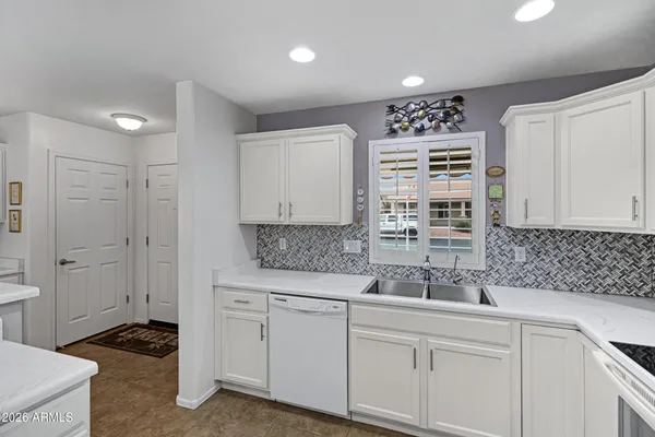 a kitchen with white cabinets and sink