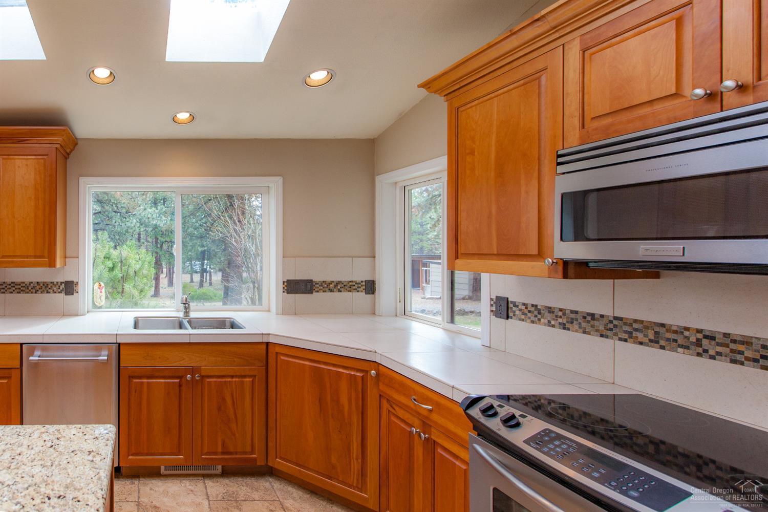 60232 East Ridgeview Drive Bend, OR 97702 - Photo 4 of 23 a kitchen with stainless steel appliances granite countertop a sink a stove a microwave cabinets and a window