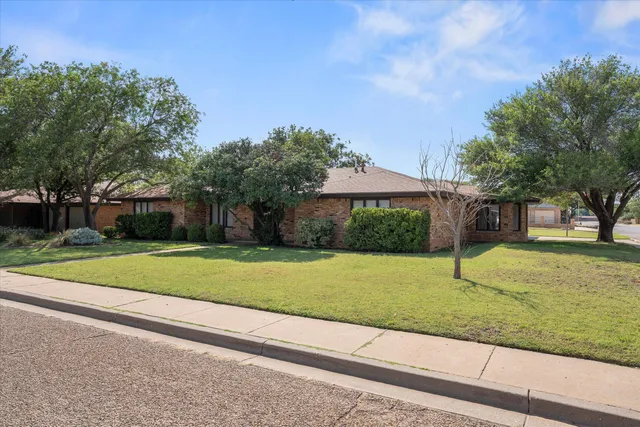 a view of a house with a yard and large tree