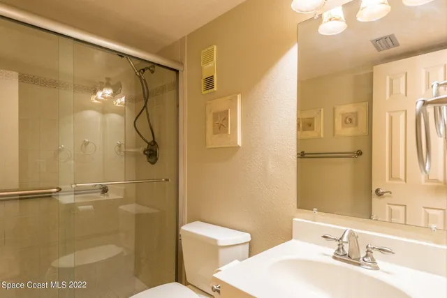 a bathroom with a granite countertop shower sink vanity and a toilet