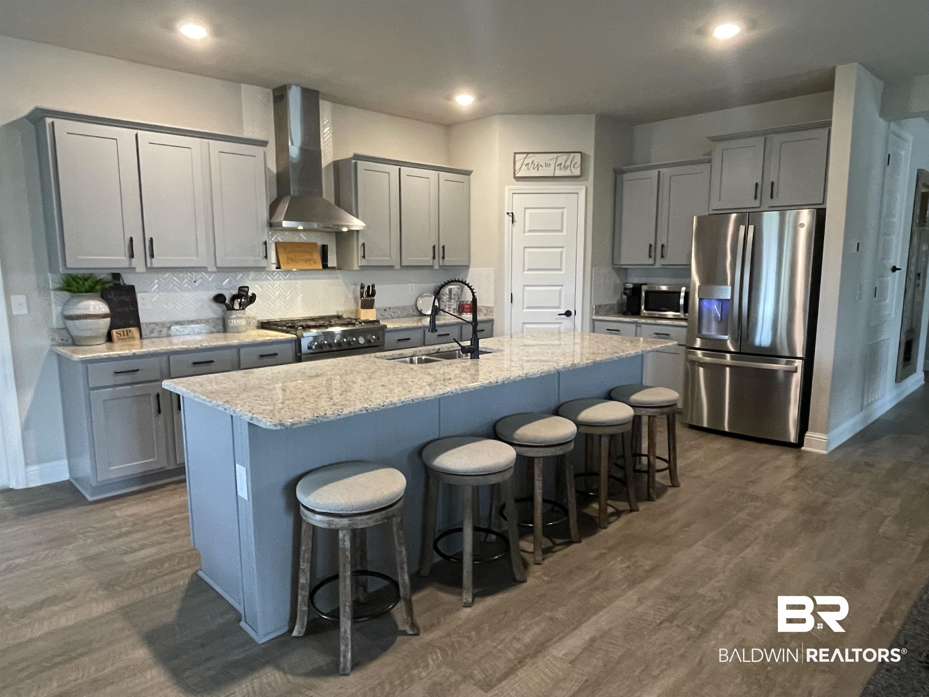 8621 Bronze Lane Foley, AL 36535 - Photo 4 of 13 Kitchen with stainless steel appliances, a center island with sink, wall chimney range hood, sink, and dark wood-type flooring