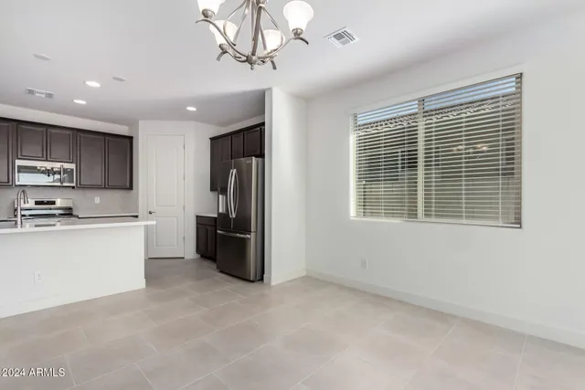 a kitchen with stainless steel appliances granite countertop a refrigerator a sink dishwasher a stove a refrigerator and a dining table with wooden floor