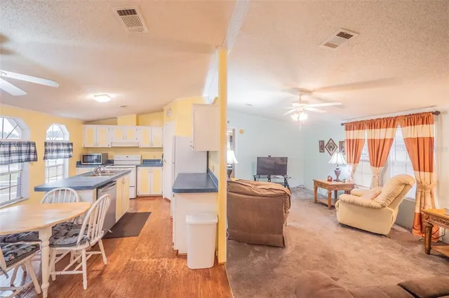 a kitchen with a sink a refrigerator a stove and chairs with wooden floor