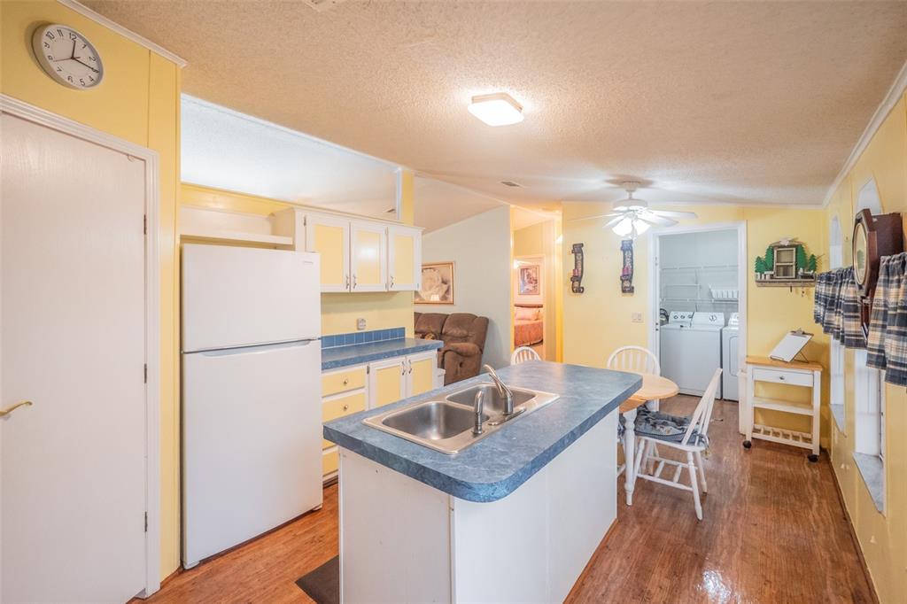37510 Quail Ridge Circle Leesburg, FL 34788 - Photo 14 of 43 a kitchen with a sink a refrigerator a stove and chairs with wooden floor