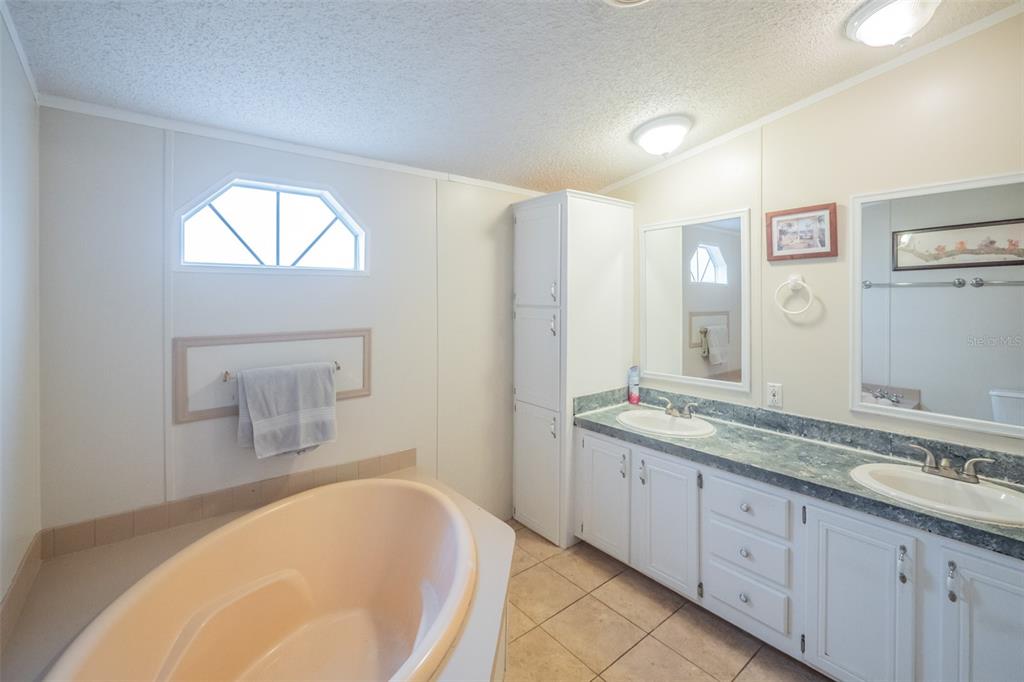37510 Quail Ridge Circle Leesburg, FL 34788 - Photo 25 of 43 a spacious bathroom with a granite countertop tub sink and mirror