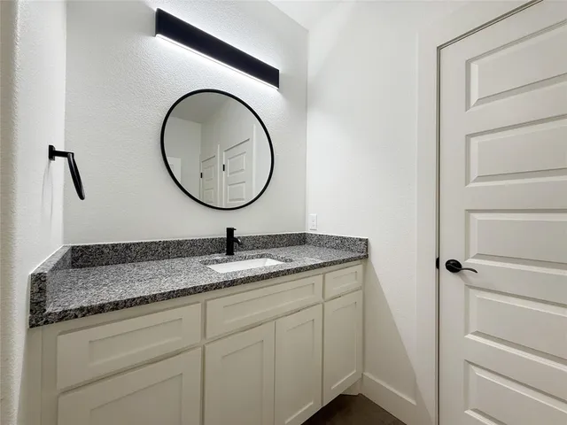a bathroom with a granite countertop sink and a mirror