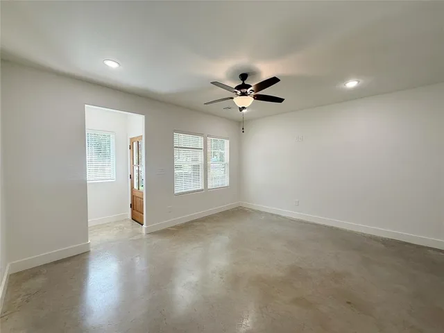 an empty room with windows and ceiling fan