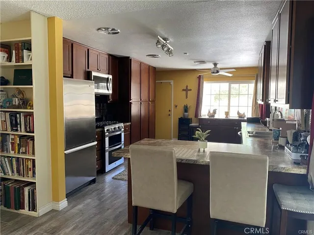 a living room with stainless steel appliances furniture a large window and a bookshelf