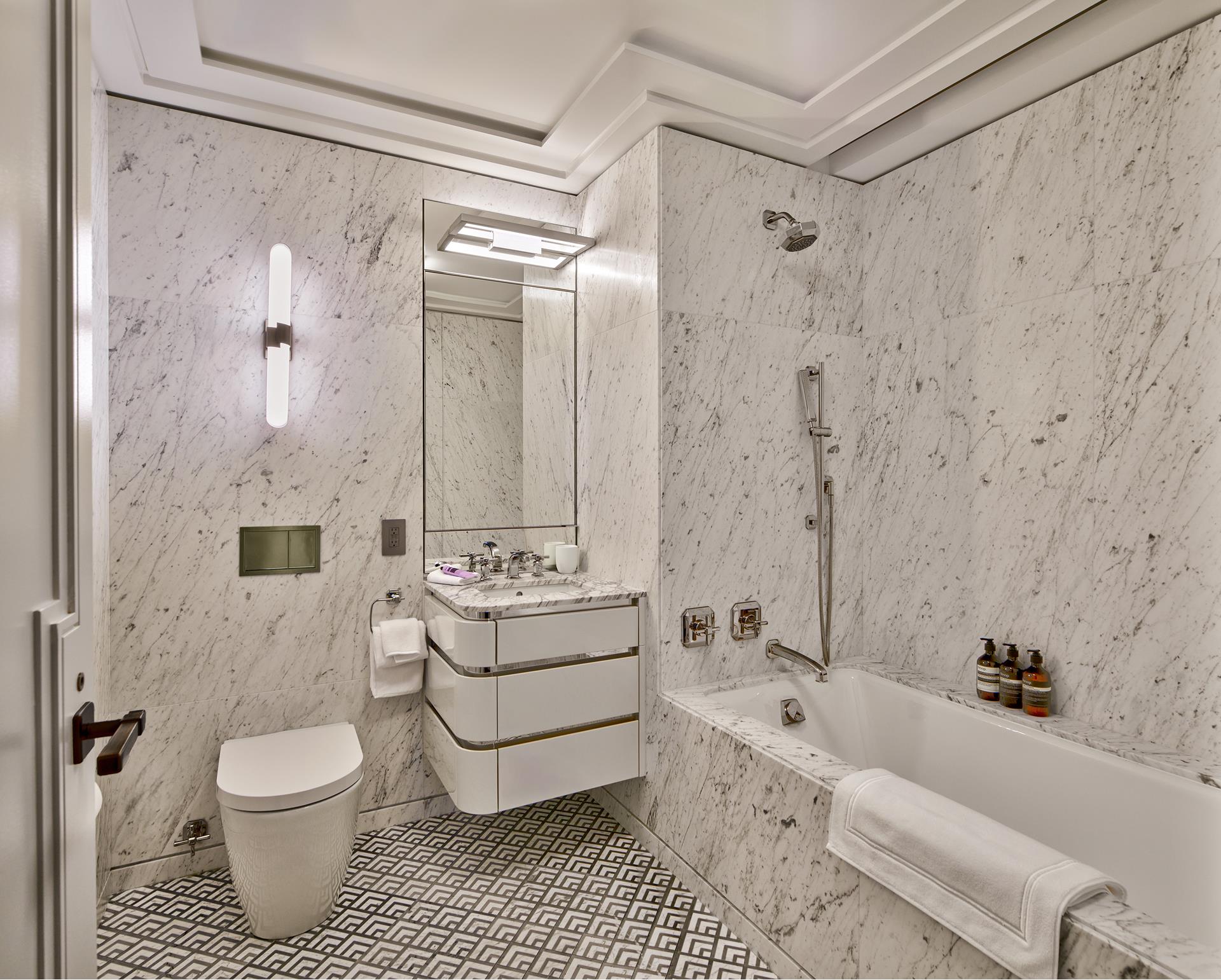 303 Park Avenue, Unit 2022 Manhattan, NY 10022 - Photo 6 of 27 a bathroom with a granite countertop toilet a sink and bathtub
