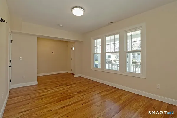 a view of an empty room with wooden floor and a window