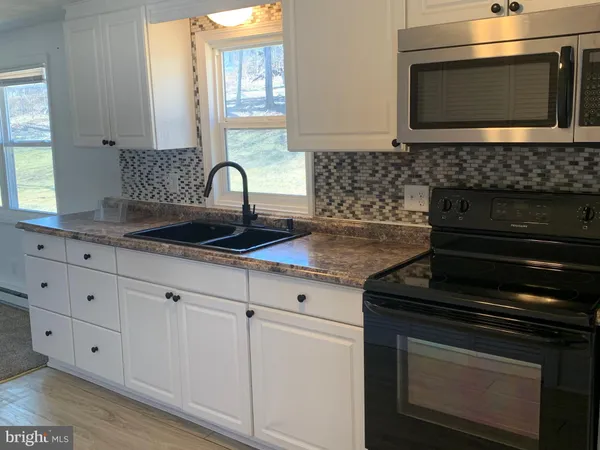 a kitchen with granite countertop white cabinets appliances and a sink