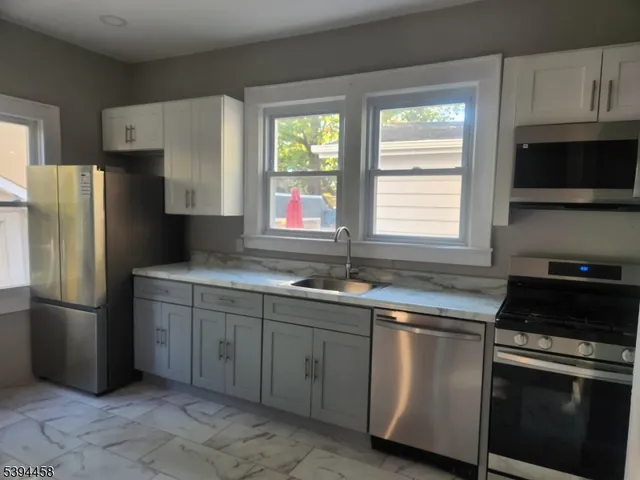 a kitchen with stainless steel appliances granite countertop a refrigerator sink and microwave