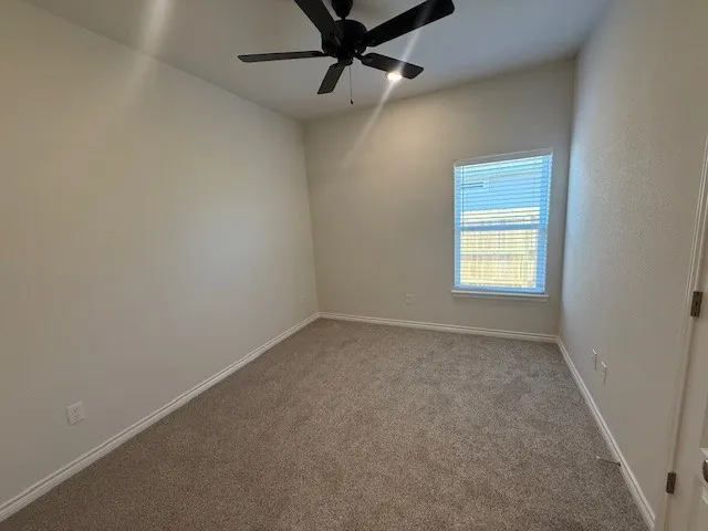 an empty room with a window and a fan