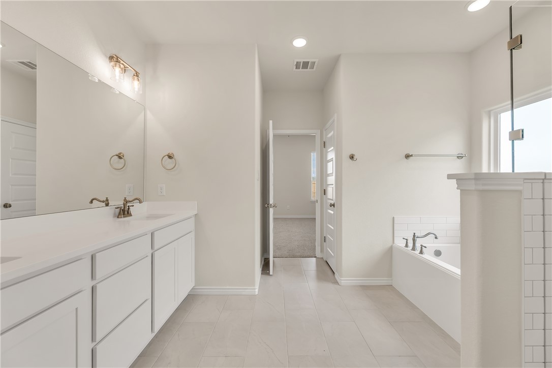 7804 Redbud Road Navasota, TX 77868 - Photo 17 of 26 a bathroom with a double vanity sink a mirror and a shower