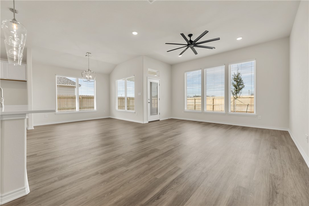7804 Redbud Road Navasota, TX 77868 - Photo 2 of 26 an empty room with wooden floor chandelier fan and windows