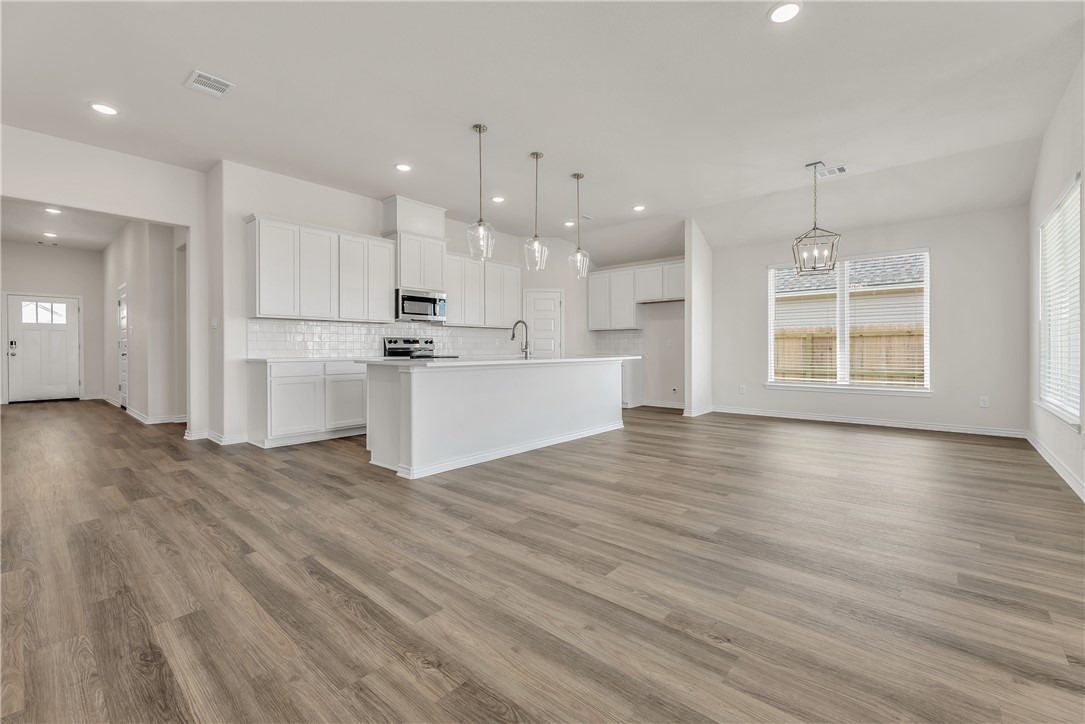 7804 Redbud Road Navasota, TX 77868 - Photo 4 of 26 an open kitchen with white cabinets and wooden floor