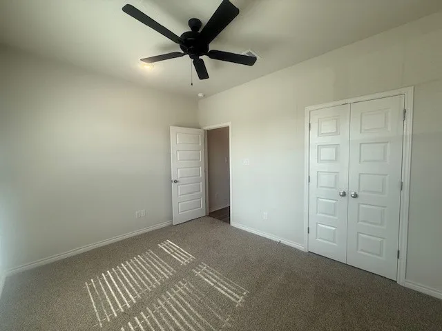 an empty room with closet and a ceiling fan