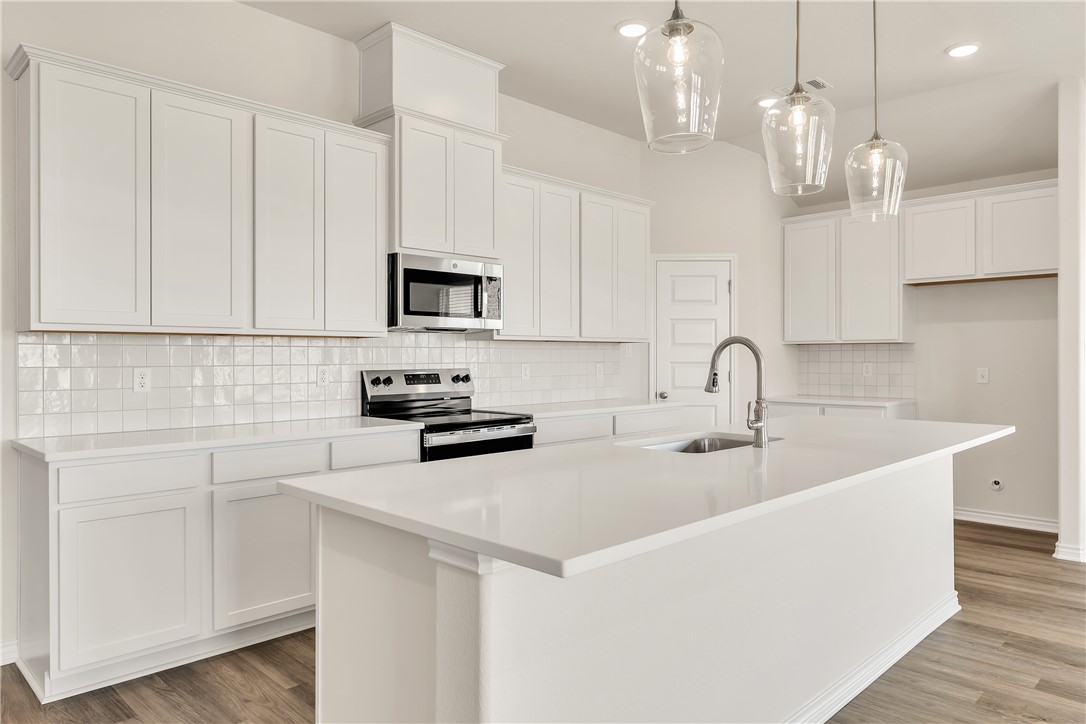 7804 Redbud Road Navasota, TX 77868 - Photo 6 of 26 a kitchen with stainless steel appliances a sink a stove a microwave a center island and cabinets