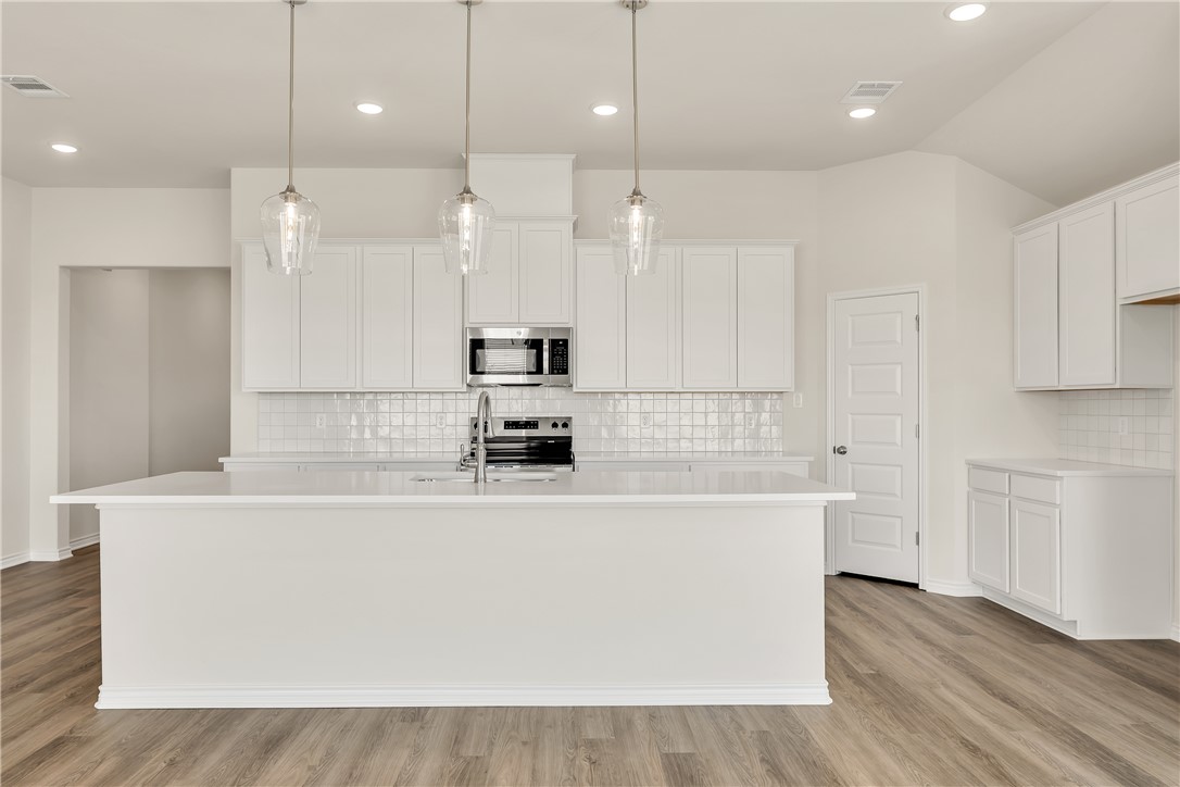 7804 Redbud Road Navasota, TX 77868 - Photo 7 of 26 a white kitchen with kitchen island a sink stainless steel appliances and cabinets