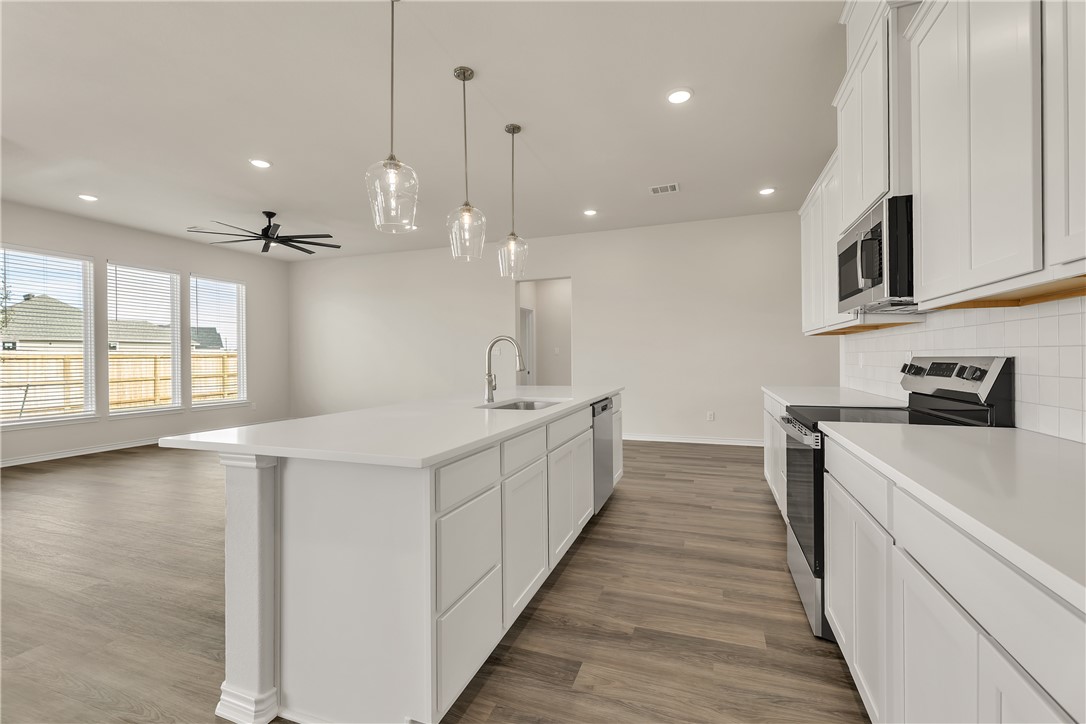 7804 Redbud Road Navasota, TX 77868 - Photo 9 of 26 a large white kitchen with a large counter top a sink a stove and wooden floor