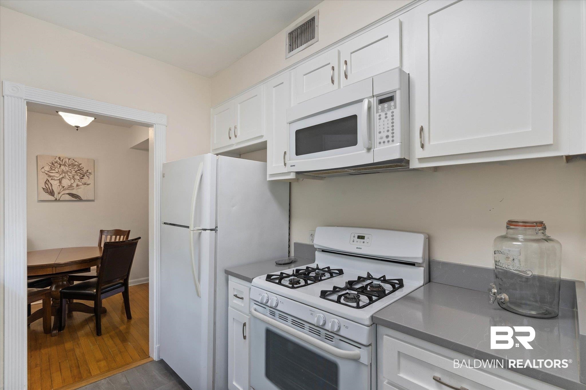 214 Upham Street, Unit 18C Mobile, AL 36607 - Photo 12 of 35 Kitchen featuring white appliances, dark wood-style floors, white cabinetry, and dark countertops