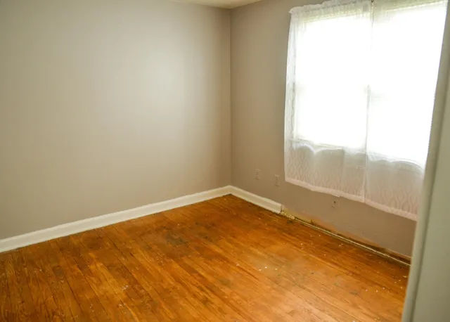 an empty room with wooden floor and a window