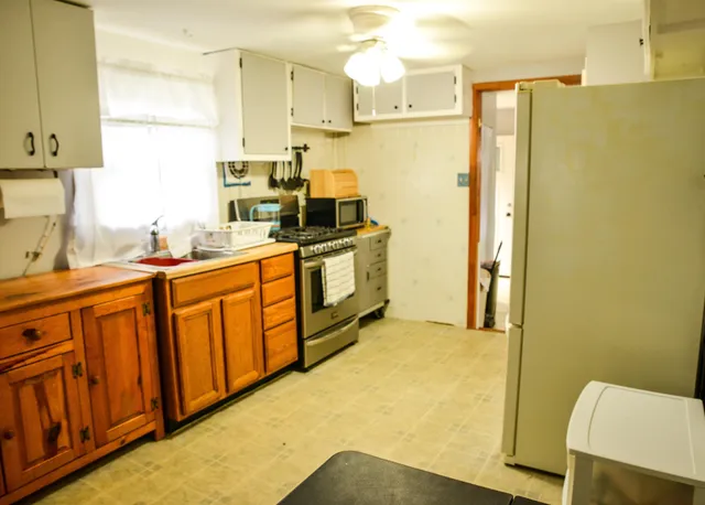 a kitchen with stainless steel appliances a stove a refrigerator a sink a counter space and cabinets