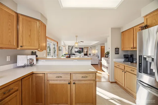 a kitchen with stainless steel appliances granite countertop a refrigerator a sink dishwasher and white cabinets with wooden floor