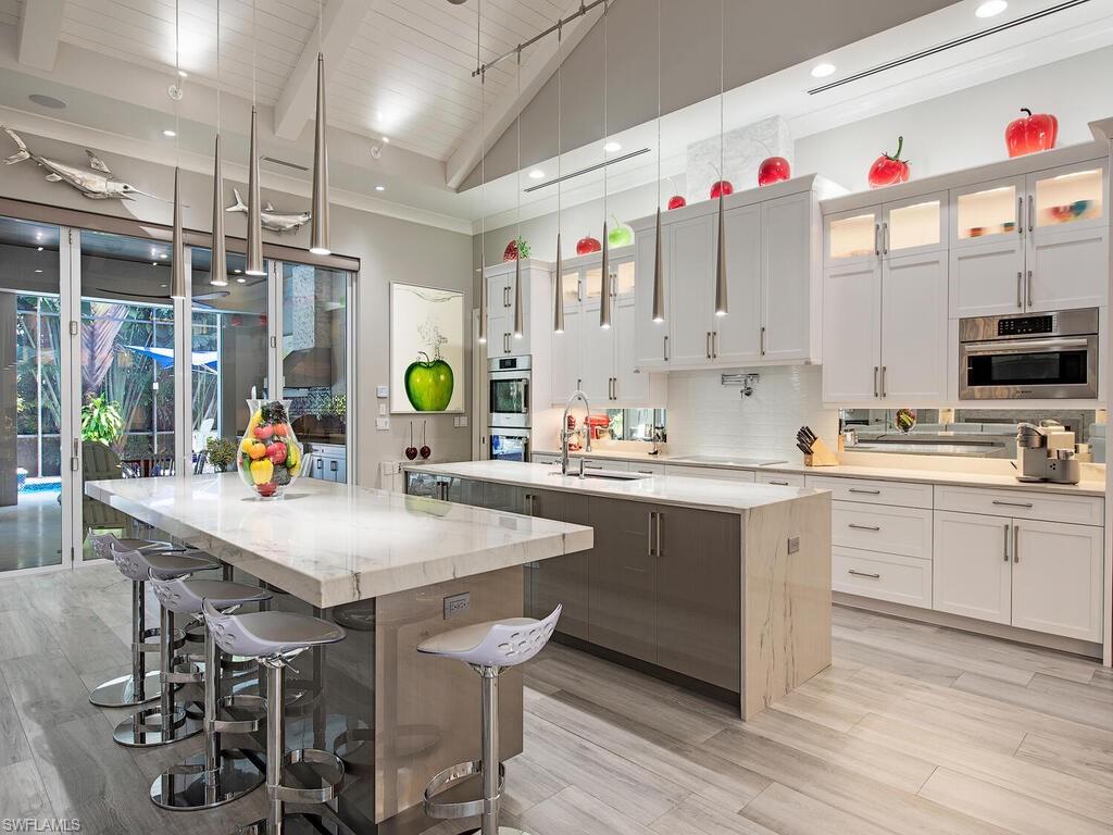 555 Mooring Line Drive Naples, FL 34103 - Photo 8 of 27 a kitchen with stainless steel appliances kitchen island granite countertop a table chairs in it and wooden floors