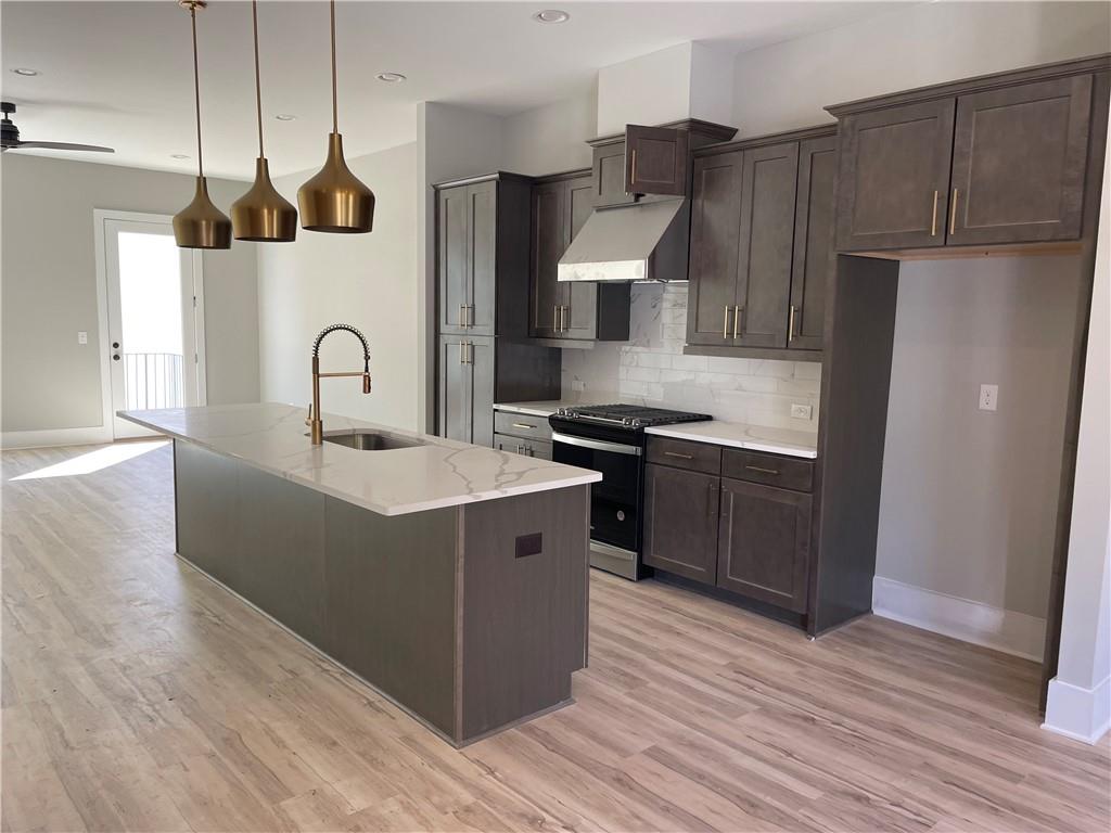 a kitchen with kitchen island stainless steel appliances a sink a counter space and wooden floor