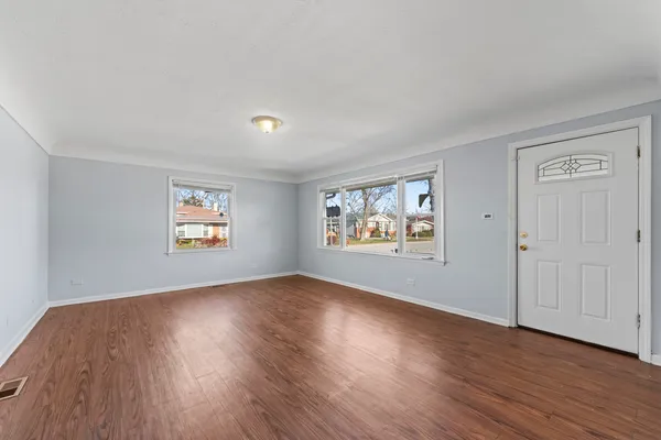 a view of an empty room with wooden floor and window