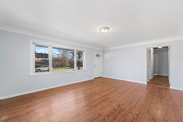 a view of an empty room with window and wooden floor