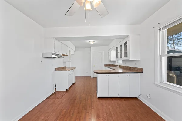 a kitchen with granite countertop a white cabinets and wooden floor