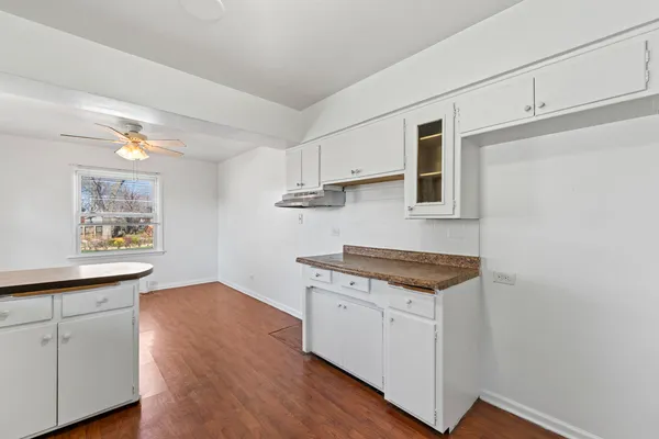 a kitchen with stainless steel appliances granite countertop a stove a sink and white cabinets with wooden floor