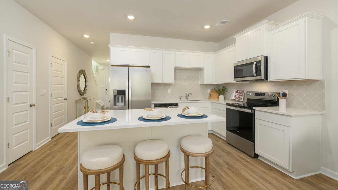 2082 Moss Hill Road Stone Mountain, GA 30088 - Photo 15 of 38 a kitchen with stainless steel appliances granite countertop a sink a stove a kitchen island and chairs with wooden floor
