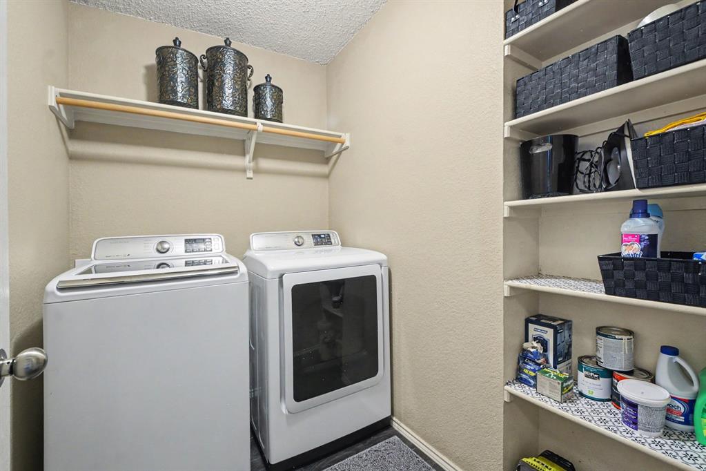 4932 Spur Ridge Court Fort Worth, TX 76244 - Photo 29 of 31 Dedicated laundry area featuring a white top-load washer, a white front-load dryer, an upper shelf with a clothing rod, and extensive built-in shelving