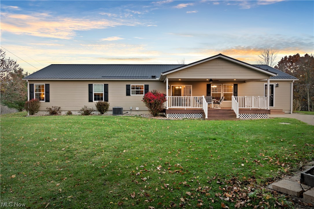 Ranch-style house featuring a yard, a wooden deck, and central AC unit