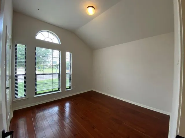 an empty room with wooden floor and windows