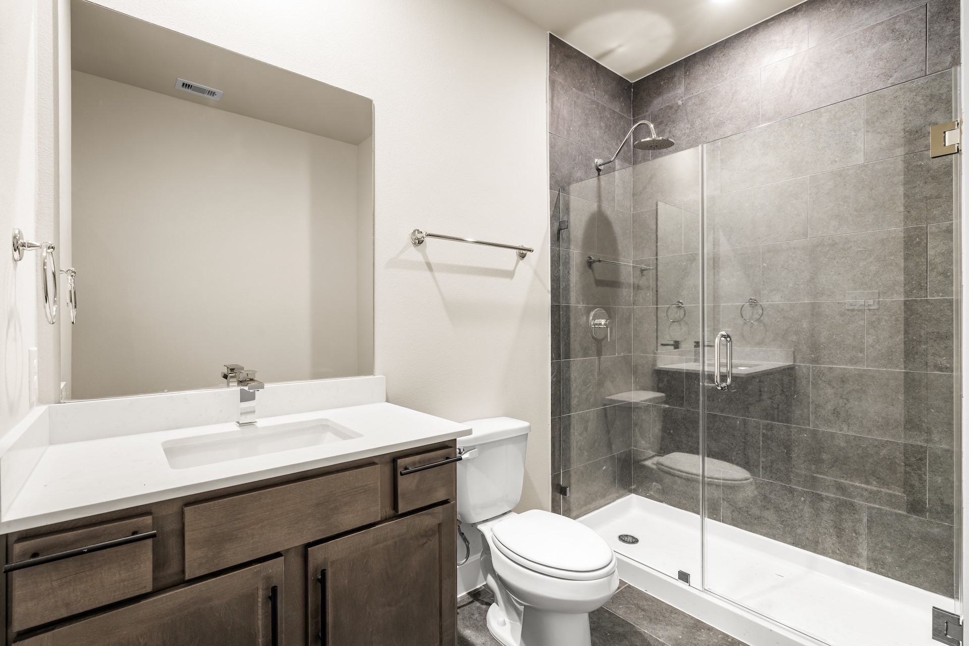 6521 Rena Street Houston, TX 77092 - Photo 19 of 24 Full secondary bathroom — quartz-topped vanity, grey tile walk-in shower with frameless glass door, chrome rain head fixture, and neutral finishes.