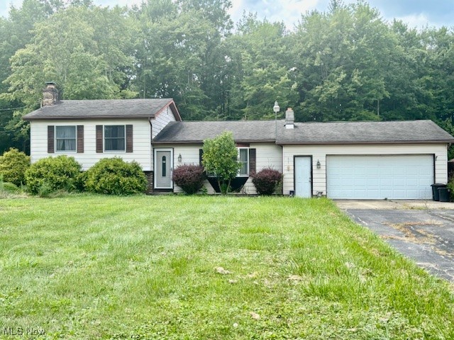 3077 Anderson Anthony Road Northwest Warren, OH 44481 - Photo 1 of 31 Split level home featuring a chimney, asphalt driveway, an attached garage, and a front lawn