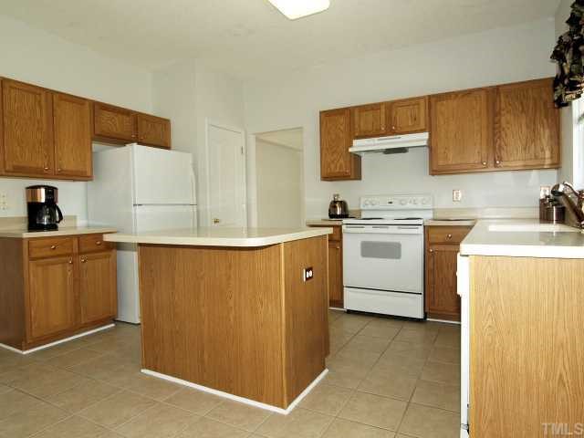 401 Grassy Point Road Apex, NC 27502 - Photo 5 of 12 Kitchen w/Beautiful Cabinetry, Updated Solid Surface Counters, Ceramic Tiled Floors and Copper Hardware. Refrigerator Included in the Sale! Window Over Sink Provides View of Back Yard.