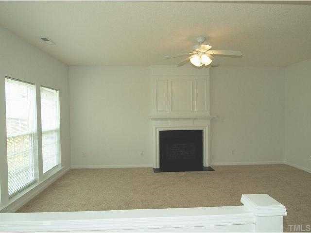 401 Grassy Point Road Apex, NC 27502 - Photo 7 of 12 Spacious Family Room w/ Gas Log Fireplace - Wall of Windows Overlooks Backyard. Detailed Mantle and New Carpeting.