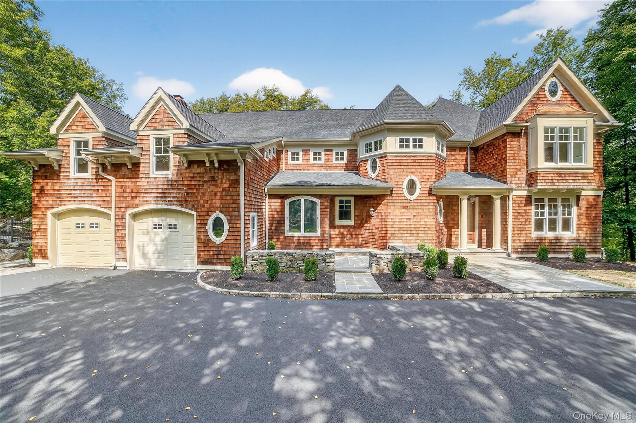 Shingle-style home featuring asphalt driveway, a shingled roof, an attached garage, and a chimney