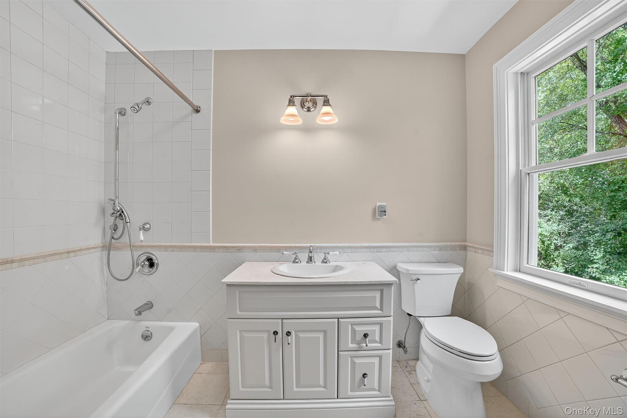 6 Todd Road Katonah, NY 10536 - Photo 31 of 50 Bathroom with tub / shower combination, vanity, tile walls, light tile patterned floors, and a wainscoted wall