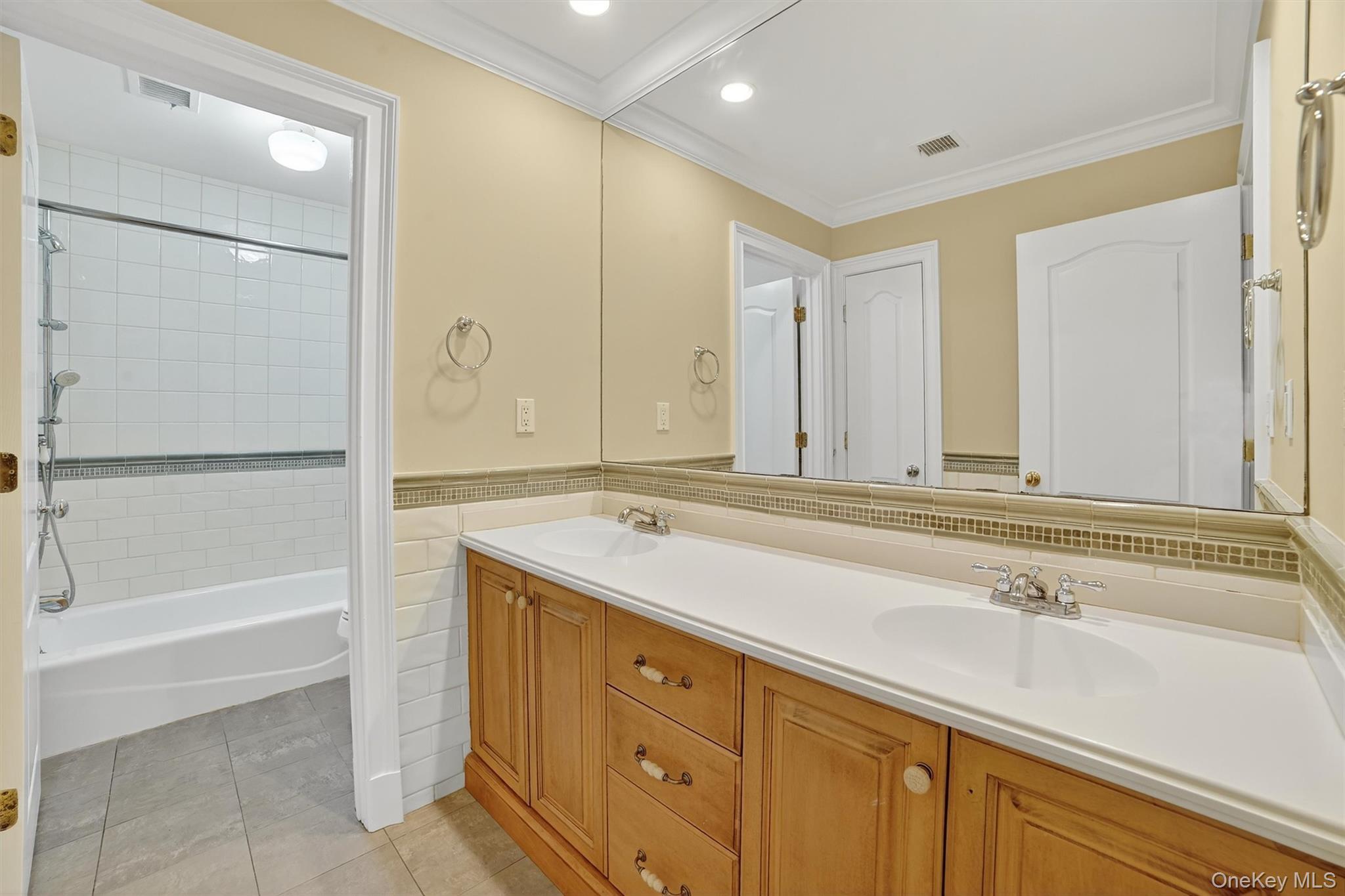 6 Todd Road Katonah, NY 10536 - Photo 35 of 50 Full bath with double vanity, light tile patterned floors, washtub / shower combination, ornamental molding, and tile walls