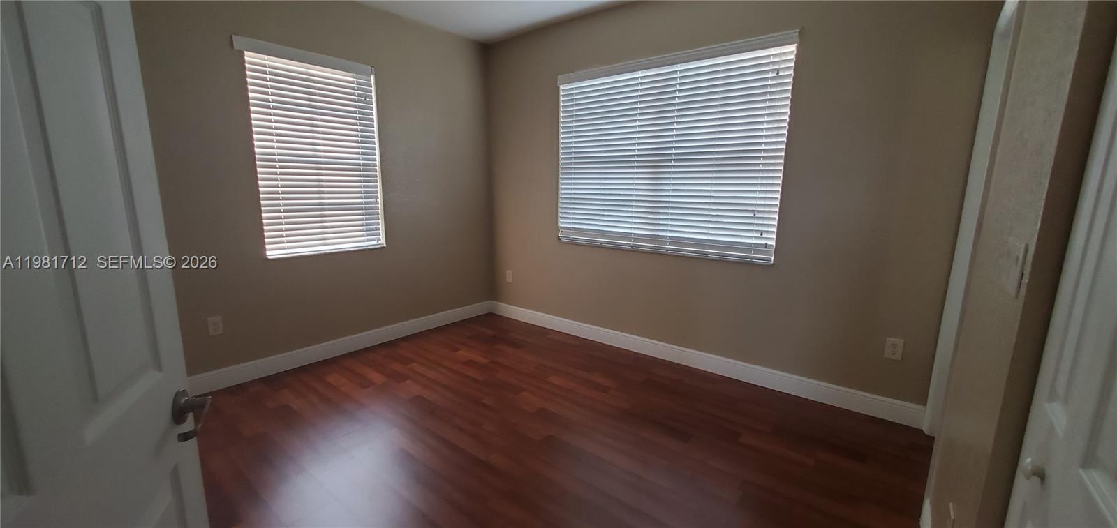 9267 Southwest 227th Street, Unit 2 Miami, FL 33190 - Photo 4 of 24 an empty room with wooden floor and windows