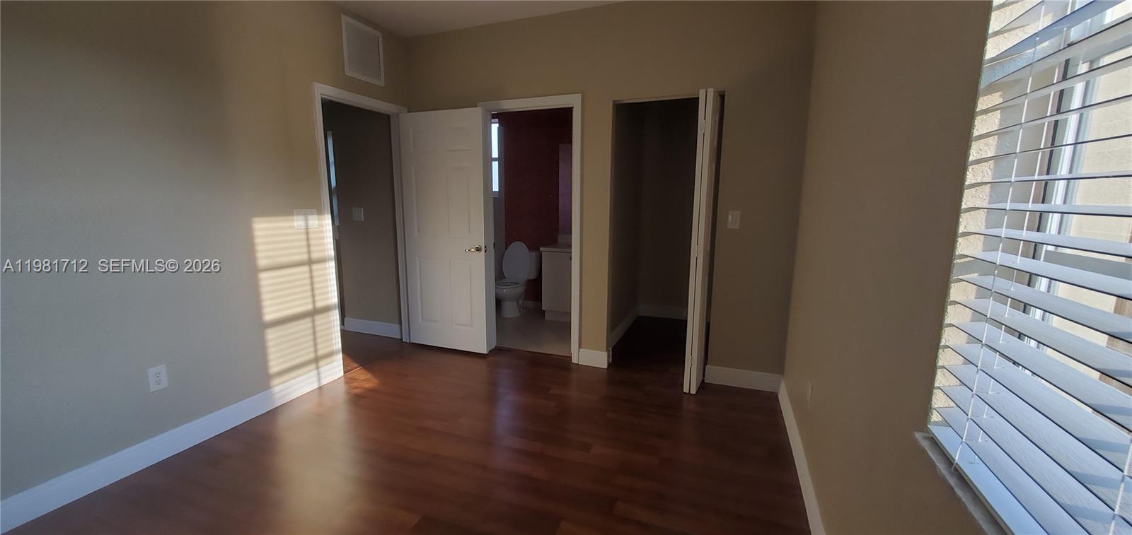 9267 Southwest 227th Street, Unit 2 Miami, FL 33190 - Photo 5 of 24 a view of an empty room with wooden floor and a window